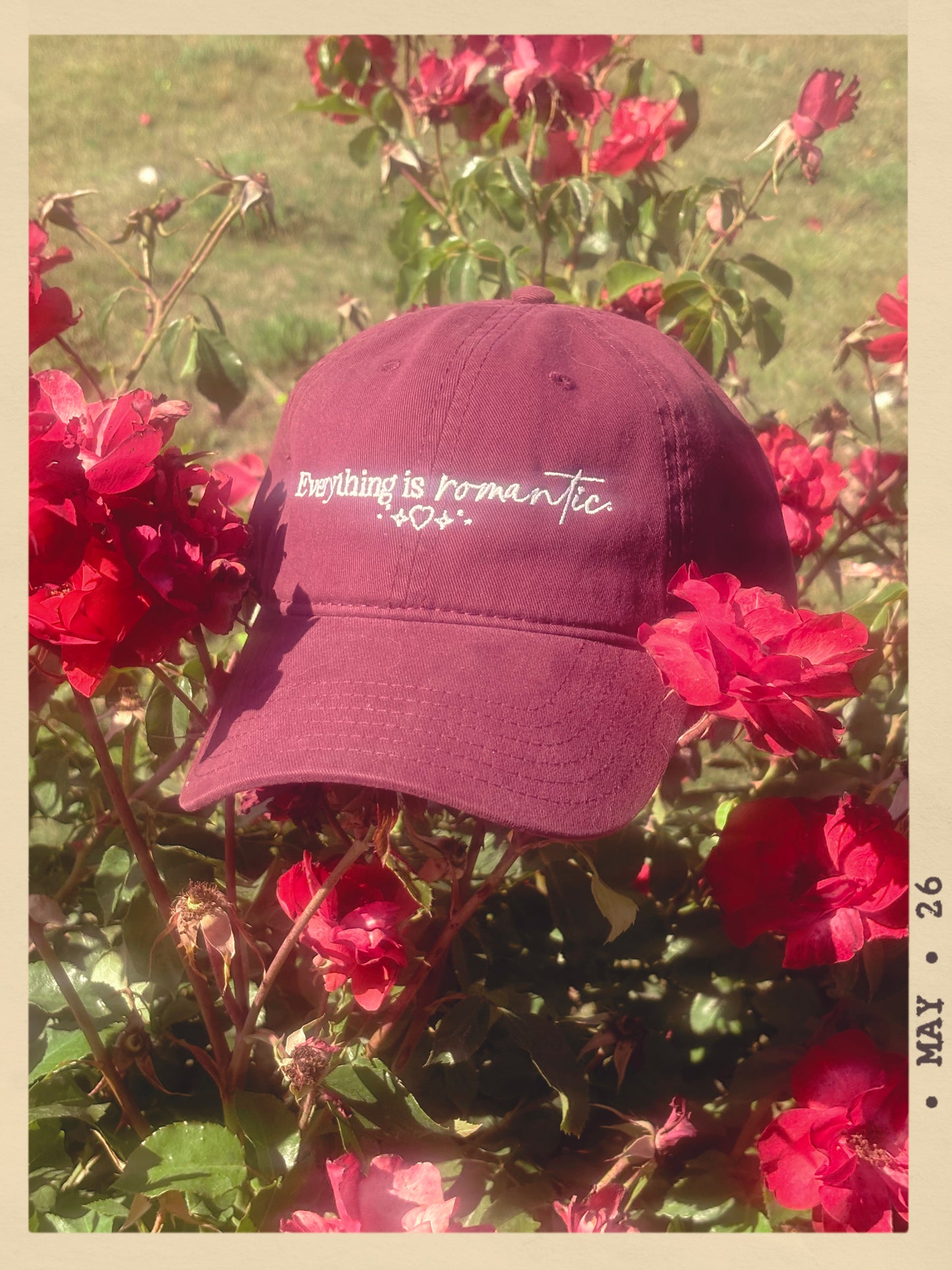 Maroon cap with 'Everything is romantic' text on a background of red flowers