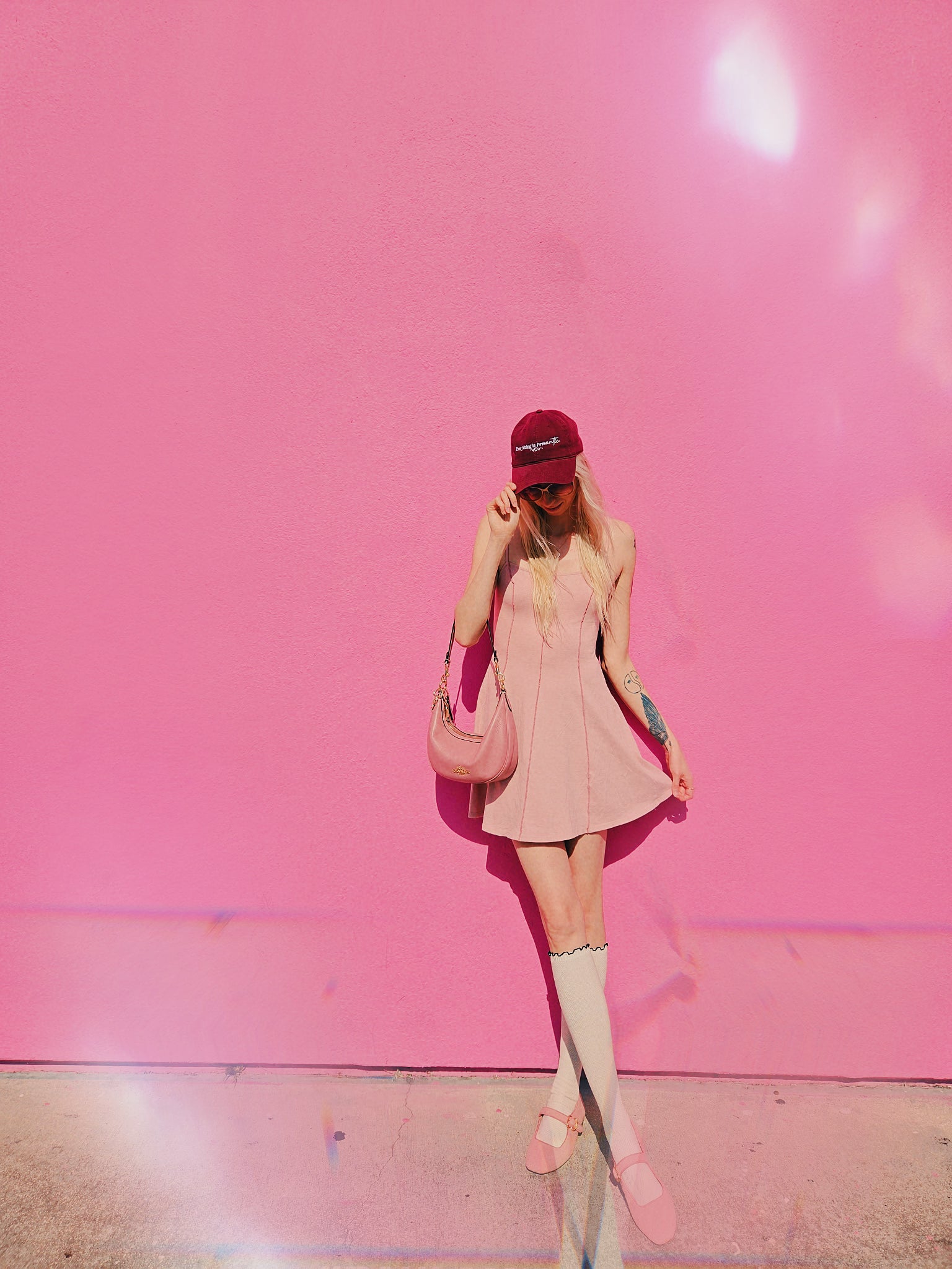Person wearing a pink dress and cap against a pink wall